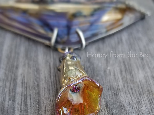 Close up of lampwork flower dangle with crystal inside