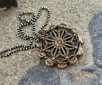 Back of mixed media pendant shows filigree back