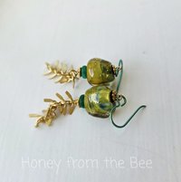Green and gold earrings feature dangling leafy chain below green and gold lampwork
