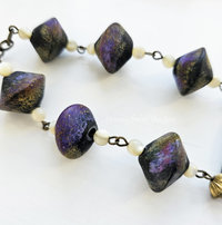 Art necklace features lampwork by Angelica Schott in shades of black, purple and gold.
