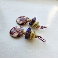 Shell earrings feature lampwork in purple, red, and touch of blue