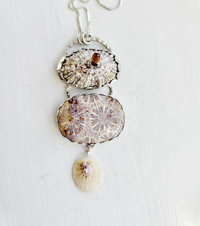 Lavender and cream beach inspired art necklace features fossilized coral agate and two found shells with a faceted tourmaline.