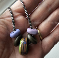 Lampwork artisan necklace features glass in purple, green and bronze