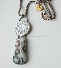 Old Stock Ocean Jasper with lily pad imagery sits below a reticulated sterling silver disc in this artisan pendant.