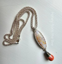 Orbicular Ocean Jasper in white and touches of orange with an orange ceramic drop pendant necklace