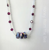 Red and blue necklace features artisan glass and garnet