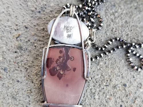 Back of Apache sage pendant shows wire frame on the apache sage cabochon and smooth sterling silver oval behind the cast pinecone.