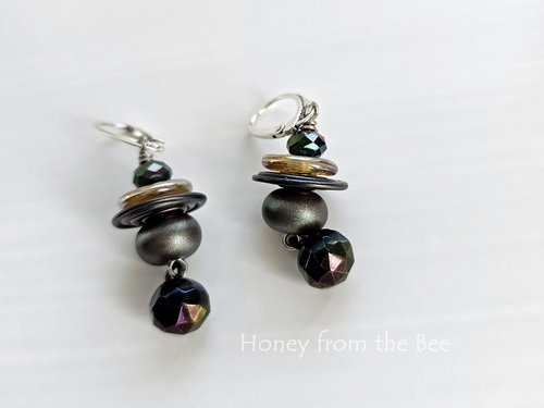 Iridescent earrings feature lampwork, crystal and antique button in shades of purple, yellow, blue, and teal