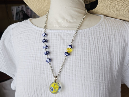 Blue and white artisan necklace with pops of yellow on model