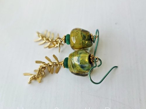 Green and gold earrings feature dangling leafy chain below green and gold lampwork