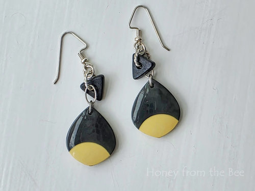 Black and cream earrings feature mixed media