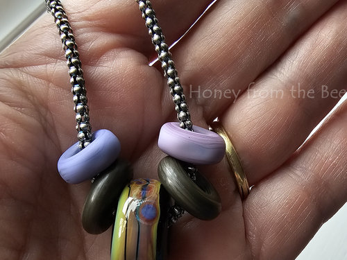 Lampwork artisan necklace features glass in purple, green and bronze