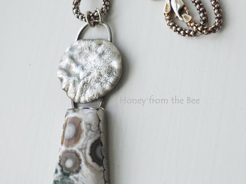 Old Stock Ocean Jasper with lily pad imagery sits below a reticulated sterling silver disc in this artisan pendant.