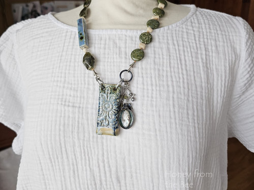 Blue and Green necklace with garnet, ceramic and vintage cameo on model
