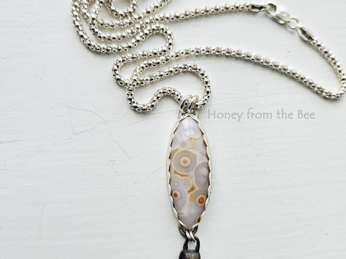 White with orange highlights ocean jasper cabochon on sterling silver chain