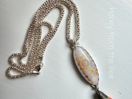 Orbicular Ocean Jasper in white and touches of orange with an orange ceramic drop pendant necklace