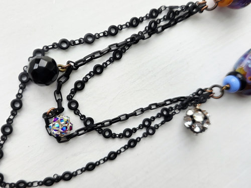 black chain dangles from crow necklace