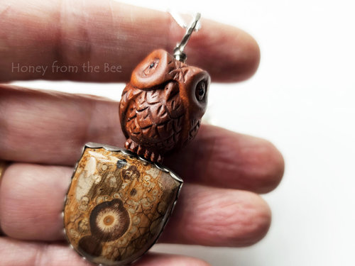 Carved wood owl sitting atop a gemstone that looks like wood - artisan pendant