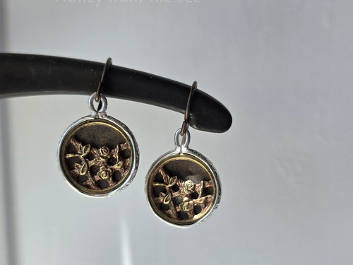 Antique button earrings feature roses on a trellis in brass and are set in sterling silver