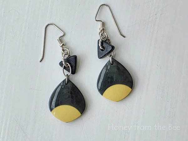 Black and cream earrings feature mixed media