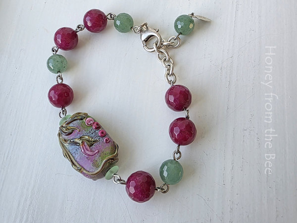 Floral bracelet features lampwork focal and beads of green and dark rose