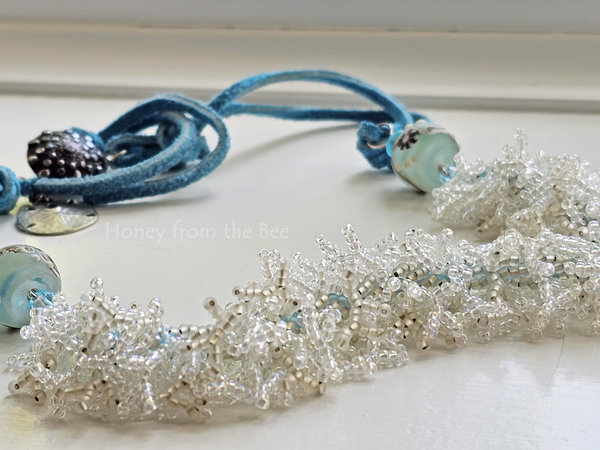 Beach necklace features a beadwoven surf in crystal and white beads